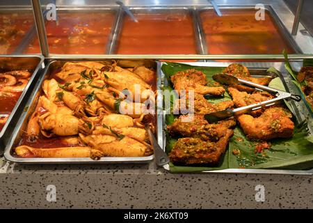 Nahaufnahme der Tintenfische und würzigen gebratenen Hähnchendrumsticks am Food Court Stand. Stockfoto