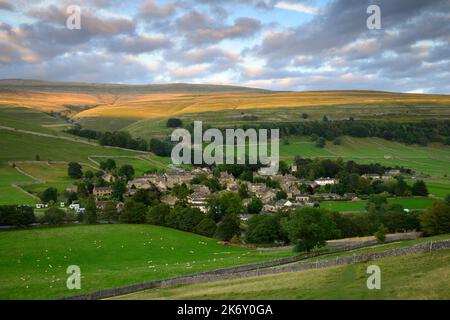 Malerisches Dorf in Dales (Hütten und Häuser), eingebettet in das Tal (steile Hänge und sonnenbeschienene Moorlandschaften) - Kettlewell, Yorkshire England. Stockfoto