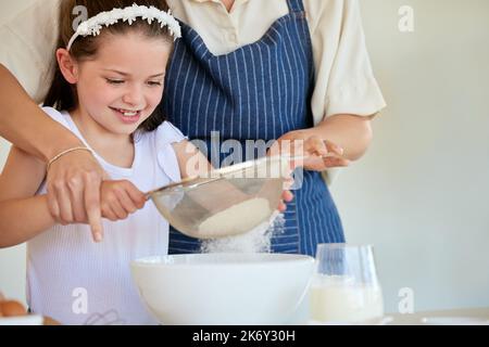 Sie kennt die besten Techniken. Ein kleines Mädchen hilft ihren Eltern, in der Küche zu Hause zu kochen. Stockfoto