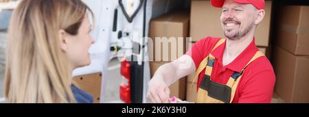 Eine Frau auf der Straße erhält ein Paket von einem Kurier Stockfoto