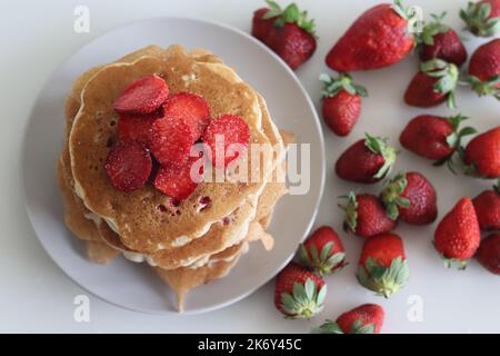 Erdbeerpfannkuchen. Weiche und flauschige Buttermilchpfannkuchen mit frischen Erdbeeren, die mit frisch geschnittenen Erdbeeren zubereitet werden, dem Teig aus Mehl hinzugefügt, b Stockfoto