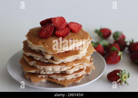 Erdbeerpfannkuchen. Weiche und flauschige Buttermilchpfannkuchen mit frischen Erdbeeren, die mit frisch geschnittenen Erdbeeren zubereitet werden, dem Teig aus Mehl hinzugefügt, b Stockfoto