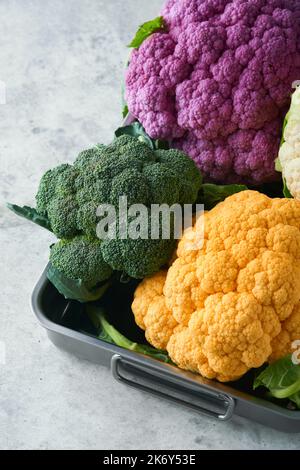 Colorfu-Blumenkohl. Verschiedene Arten von Blumenkohl auf grauem Beton Hintergrund. Violette, gelbe, weiße und grüne Farbkabbage. Brokkoli und Romanesco. Stockfoto