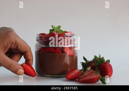 Schokoladenpudding mit Erdbeere. Schokoladenpudding serviert mit frisch gehackten Erdbeeren. Ein schnelles und einfaches Dessert, serviert in einer Glasflasche. Schuss auf WH Stockfoto