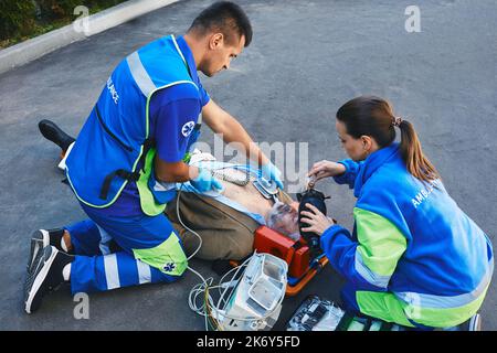 Team von Sanitätern, die die HLW mit einem mobilen Defibrillator durchführen und einen manuellen Beatmungsgerät für den Patienten vorbereiten. Erste Hilfe und HLW durch Rettungskräfte Stockfoto