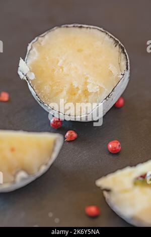 Eine Nahansicht der belper-Kugeln mit Knoblauch und rosa Pfeffer in Holzasche. Schweizer Käse. Milchig fermentierter Käse. SDOF Stockfoto