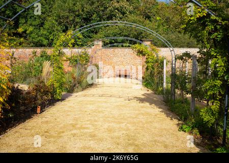 Im Kirkleatham ummauerten Garten ein Platz an einer Wand mit Blick auf einen offenen Weg durch den Blumengarten Stockfoto