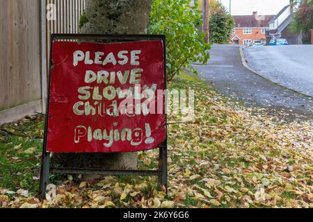 Bitte fahren Sie langsam spielende Kinder, rotes Straßenschild in Wohngebiet, Großbritannien Stockfoto