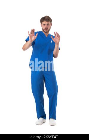 Junge männliche medizinische Krankenschwester Healthcare worker zeigt Stop-Zeichen isoliert auf weißem Hintergrund voller Länge Studio Porträt Stockfoto