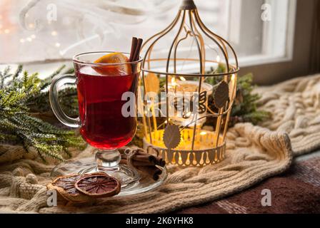 Glühwein mit Zitrusfrüchten und Gewürzen. Wintergrog mit Orange und Zimt auf einem Hintergrund des Neujahrsdekors Stockfoto