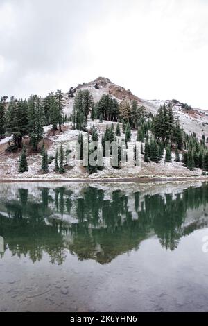 Vulkanischer See in den verschneiten Bergen. Ridge Lakes im Lassen Volcanic National Park in Kalifornien. Reflektierender Bergsee Stockfoto