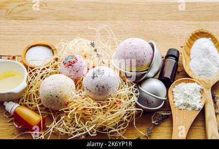 Das Konzept der Herstellung von kohlensäurehaltigen Badebomben zu Hause. Alle Zutaten auf dem Tisch auf Holzlöffeln: Maisstärke, ätherisches Öl, Farbstoff, Zitronensäure, Backpulver. Stockfoto