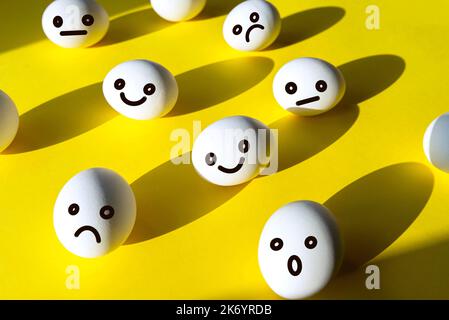 Konzeptbild über Emotionalität mit glücklichen, unglücklichen, wütenden und überraschenden Eiergesichtern auf gelbem Hintergrund, Kreativitäts-Collage Stockfoto