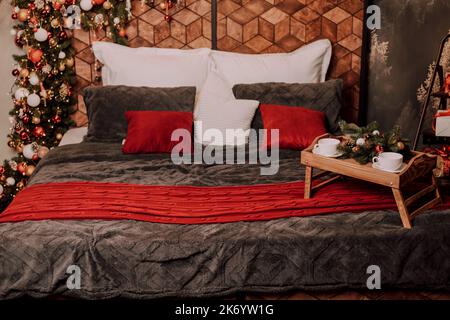 Holzbett mit Kissen und Weihnachtsschmuck. Kaffee im Bett Stockfoto