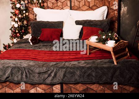 Holzbett mit Kissen und Weihnachtsschmuck. Kaffee im Bett Stockfoto