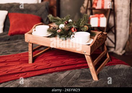 Holzbett mit Kissen und Weihnachtsschmuck. Kaffee im Bett Stockfoto