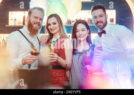 Diverse glückliche junge Freunde, die auf der Party einen Drink genießen Stockfoto