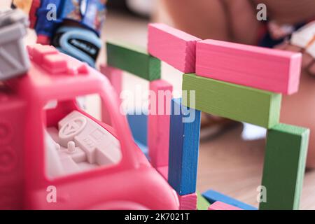 Einige bunte Spielzeughölzer und ein Van, der auf einem Hartholzboden auf einem Indoor-Spielplatz zusammenbricht Stockfoto