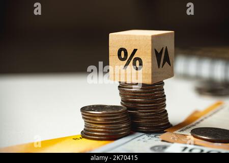 Das Konzept der Anhebung und Senkung des Zinssatzes. Würfel auf einen Stapel von Münzen und anderem Geld. Stockfoto