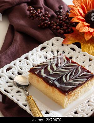 Trilece (Tres leches) Kuchen mit frischer Milch, Kondensmilch, schwerer Rahm und Karamellsauce auf der weißen Keramikplatte auf der Blumendeko serviert Stockfoto