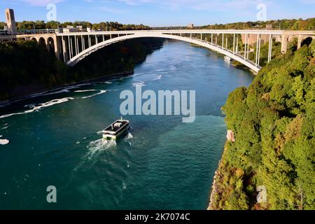 Leeres Touristenboot auf dem Niagara River unterhalb der Regenbogenbrücke zwischen Kanada und den USA Stockfoto