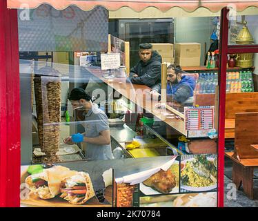 Das Innere der Kebab-Pizza zum Mitnehmen von Fast-Food-Räumlichkeiten, die von einer öffentlichen Straße durch das Fenster betrachtet werden Stockfoto