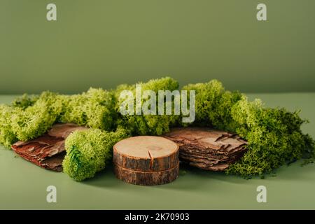 Zusammensetzung aus Rindenbaum und Moos auf warmem grünem Hintergrund. Abstraktes Podium für Bio-Kosmetikprodukte. Natürlicher Stand für Präsentation und Ausstellungen. Minimalistisches Design Stockfoto