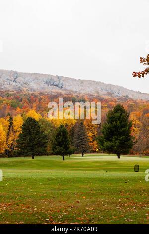 Wausau, Wisconsin Golfplatz mit einem Teil des Skigebiets Granite Peak im Hintergrund mit bunten Herbstblättern und einem leichten Schneestaub im Oktober, Stockfoto