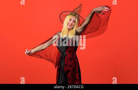 Lächelnde Frau in langen schwarzen Kleid tanzen und zaubern. Halloween Party Mädchen in Hexenhut. Stockfoto