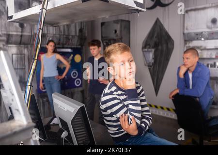 Nachdenklicher Teenager Junge, der Rätsel im Fluchtzimmer löst Stockfoto