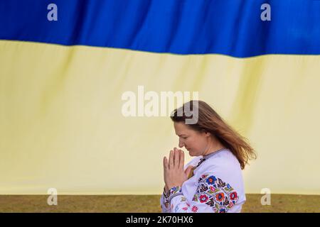 Gebet für die Ukraine junge Frau betet für die Ukraine in der Nähe der ukrainischen Flagge Stockfoto