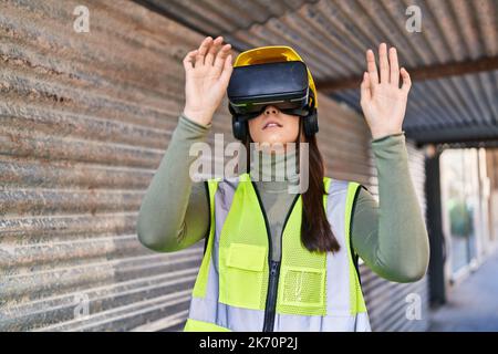 Junge schöne hispanische Architektin mit Virtual-Reality-Brille auf der Straße Stockfoto