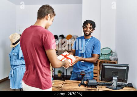 Zwei Männer, Ladenbesitzer und Kunde, die ein Geschenk im Bekleidungsgeschäft halten Stockfoto
