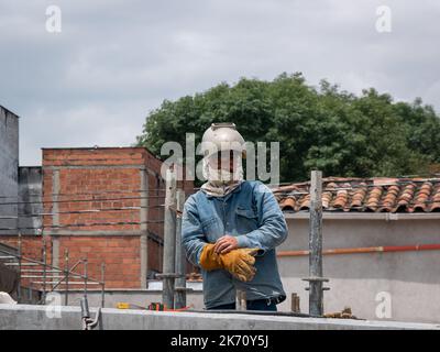 Medellin, Antioquia, Kolumbien - Juni 2 2022: Arbeiter trägt eine Schweißermaske auf dem Bau der neuen Fahrbahn Stockfoto