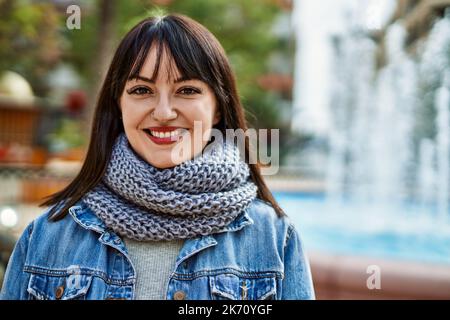 Junge Brünette Frau lächelt glücklich im Park Stockfoto