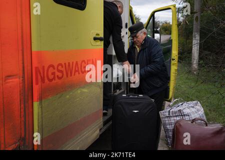 Lyman, Ukraine. 14. Oktober 2022. Die Bewohner von Lyman sahen, wie sie ihr Gepäck in den Evakuierungsbus legten. Obwohl in der Ostukraine mehr Siedlungen befreit wurden, sind viele große Infrastrukturen nach wie vor durch den Krieg beschädigt. Die Bewohner von Lyman leben ohne Strom, Gas und fließendes Wasser. Die Behörden sind sich nicht sicher, ob sie diese Dienste in naher Zukunft wiederherstellen könnten. Während sich einige Bewohner Sorgen machen, als der Winter naht und mit dem Sammeln von Brennholz begonnen hat, beschlossen einige, in eine nahe gelegene Stadt mit besserer Infrastruktur evakuiert zu werden. Kredit: SOPA Images Limited/Alamy Live Nachrichten Stockfoto