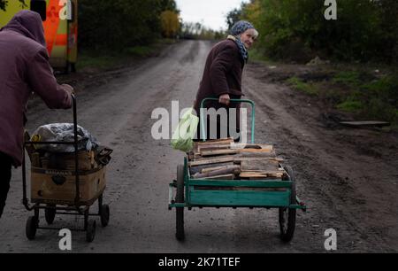 Lyman, Ukraine. 14. Oktober 2022. Der Bewohner von Lyman sah, wie er einen Wagen mit Holzstämmen zog. Obwohl in der Ostukraine mehr Siedlungen befreit wurden, sind viele große Infrastrukturen nach wie vor durch den Krieg beschädigt. Die Bewohner von Lyman leben ohne Strom, Gas und fließendes Wasser. Die Behörden sind sich nicht sicher, ob sie diese Dienste in naher Zukunft wiederherstellen könnten. Während sich einige Bewohner Sorgen machen, als der Winter naht und mit dem Sammeln von Brennholz begonnen hat, beschlossen einige, in eine nahe gelegene Stadt mit besserer Infrastruktur evakuiert zu werden. Kredit: SOPA Images Limited/Alamy Live Nachrichten Stockfoto