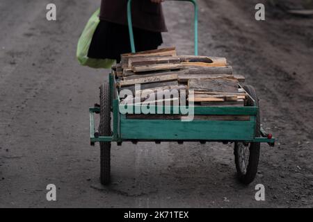 Lyman, Ukraine. 14. Oktober 2022. Ein Bewohner von Lyman sah, wie er einen Trolley aus Baumstämmen zog. Obwohl in der Ostukraine mehr Siedlungen befreit wurden, sind viele große Infrastrukturen nach wie vor durch den Krieg beschädigt. Die Bewohner von Lyman leben ohne Strom, Gas und fließendes Wasser. Die Behörden sind sich nicht sicher, ob sie diese Dienste in naher Zukunft wiederherstellen könnten. Während sich einige Bewohner Sorgen machen, als der Winter naht und mit dem Sammeln von Brennholz begonnen hat, beschlossen einige, in eine nahe gelegene Stadt mit besserer Infrastruktur evakuiert zu werden. Kredit: SOPA Images Limited/Alamy Live Nachrichten Stockfoto