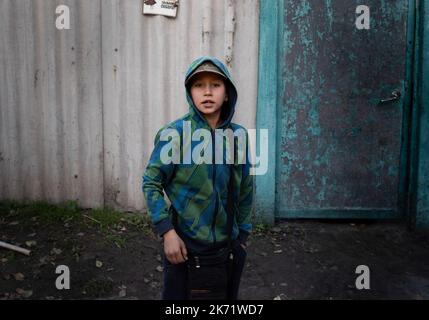 Lyman, Ukraine. 14. Oktober 2022. Andre, 9, sah, wie er darum bat, aus seinem Haus in Lyman evakuiert zu werden. Sein Vater, der auch sein Vormund ist, erlaubte es jedoch nicht. Obwohl in der Ostukraine mehr Siedlungen befreit wurden, sind viele große Infrastrukturen nach wie vor durch den Krieg beschädigt. Die Bewohner von Lyman leben ohne Strom, Gas und fließendes Wasser. Die Behörden sind sich nicht sicher, ob sie diese Dienste in naher Zukunft wiederherstellen könnten. Während sich einige Bewohner Sorgen machen, als der Winter naht und mit dem Sammeln von Brennholz begonnen hat, beschlossen einige, in eine nahe gelegene Stadt mit besserer Infrastruktur evakuiert zu werden. Stockfoto