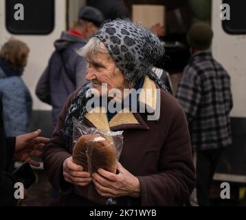 Lyman, Ukraine. 14. Oktober 2022. Ein Bewohner von Lyman sah ein Lächeln, nachdem er im Rahmen der humanitären Hilfe ein Brot erhalten hatte. Obwohl in der Ostukraine mehr Siedlungen befreit wurden, sind viele große Infrastrukturen nach wie vor durch den Krieg beschädigt. Die Bewohner von Lyman leben ohne Strom, Gas und fließendes Wasser. Die Behörden sind sich nicht sicher, ob sie diese Dienste in naher Zukunft wiederherstellen könnten. Während sich einige Bewohner Sorgen machen, als der Winter naht und mit dem Sammeln von Brennholz begonnen hat, beschlossen einige, in eine nahe gelegene Stadt mit besserer Infrastruktur evakuiert zu werden. (Bild: © As Stockfoto