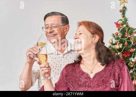 Ein glückliches lateinisches Paar, das zu Weihnachten oder Neujahr toastiert, zu Hause Feiertage feiert und eine gute Zeit miteinander hat. Stockfoto