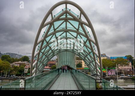 Die Friedensbrücke ist eine bogenförmige Fußgängerbrücke, eine Stahl- und Glaskonstruktion, die den Fluss Kura in Tiflis überquert Stockfoto