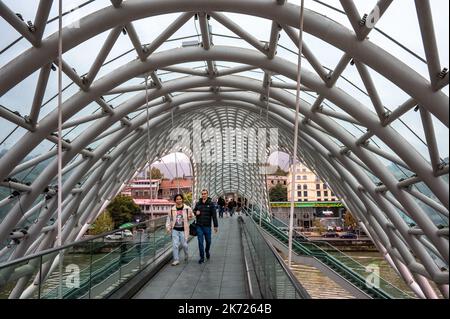 Die Friedensbrücke ist eine bogenförmige Fußgängerbrücke, eine Stahl- und Glaskonstruktion, die den Fluss Kura in Tiflis überquert Stockfoto