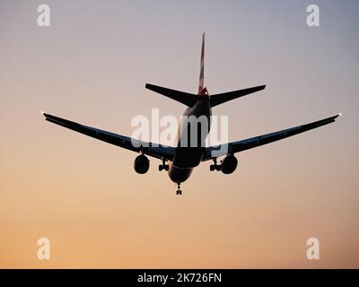 Richmond, British Columbia, Kanada. 16. Oktober 2022. Ein Boeing 777-200ER-Jetliner (G-YMMT) von British Airways landet in der Dämmerung aufgrund von Waldbränden am Vancouver International Airport in rauchigem Dunst. (Bild: © Bayne Stanley/ZUMA Press Wire) Stockfoto