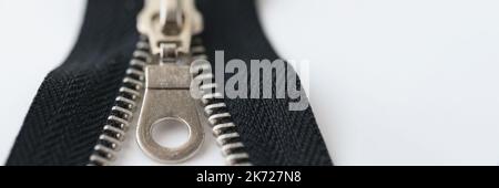 Nahaufnahme Makroaufnahme eines offenen schwarzen Messing-Reißverschlusses auf weißem Hintergrund isoliert Stockfoto