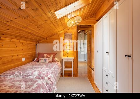 Schmale Schlafzimmer mit Betten und weißem Kleiderschrank in einem modernen Ferienhaus mit Holzwänden. Stockfoto