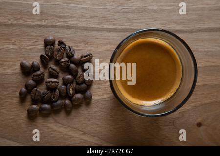 Geröstete Kaffeebohnen mit Espresso in einer Glasschale Stockfoto