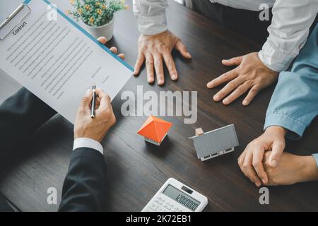 Home Sales und Home Insurance Konzept. Immobilienmakler sprach über die Bedingungen des Hauskaufvertrags und bat den Kunden, das Dokument zu unterzeichnen Stockfoto