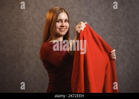 Schönes Mädchen versucht auf einem roten Pullover Stockfoto