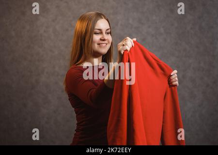 Schönes Mädchen versucht auf einem roten Pullover Stockfoto